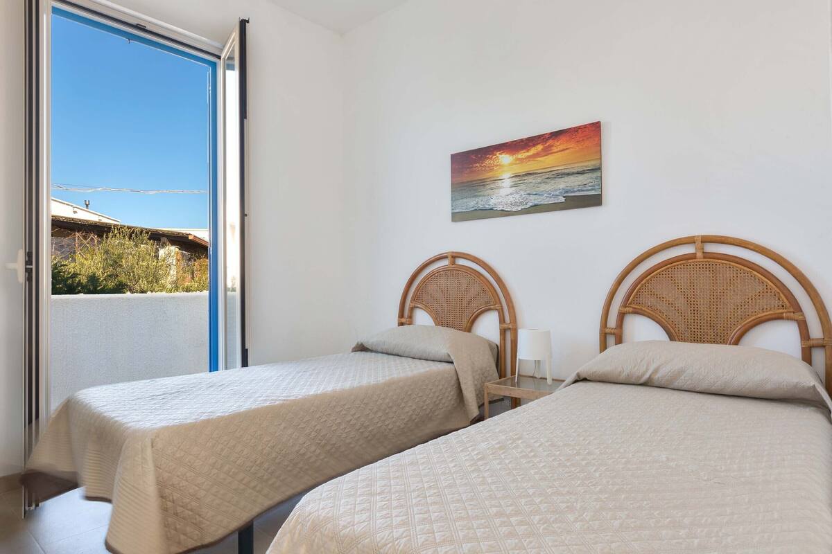 Een kamer met twee bedden, een schilderij van een zonsondergang en uitzicht op het omliggende landschap.