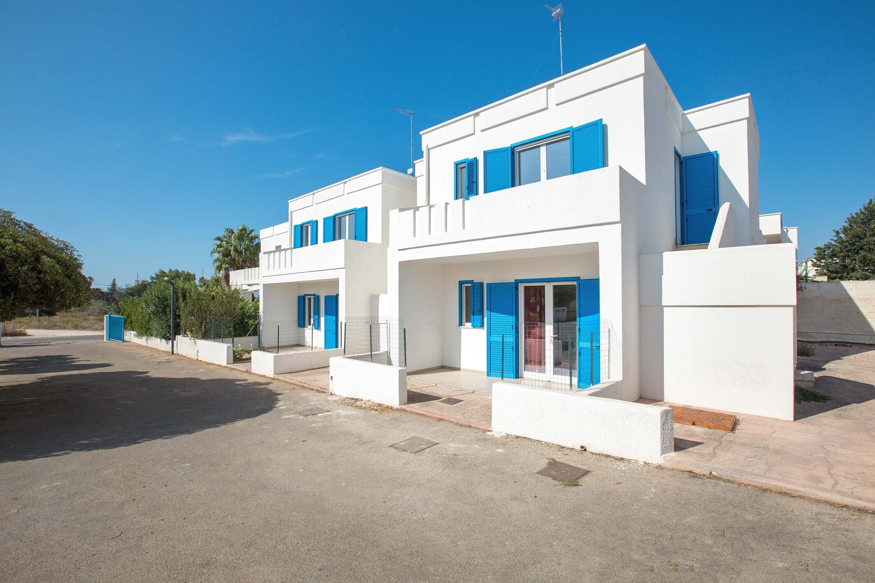 Un edificio moderno blanco con contraventanas azules y un cielo azul despejado.