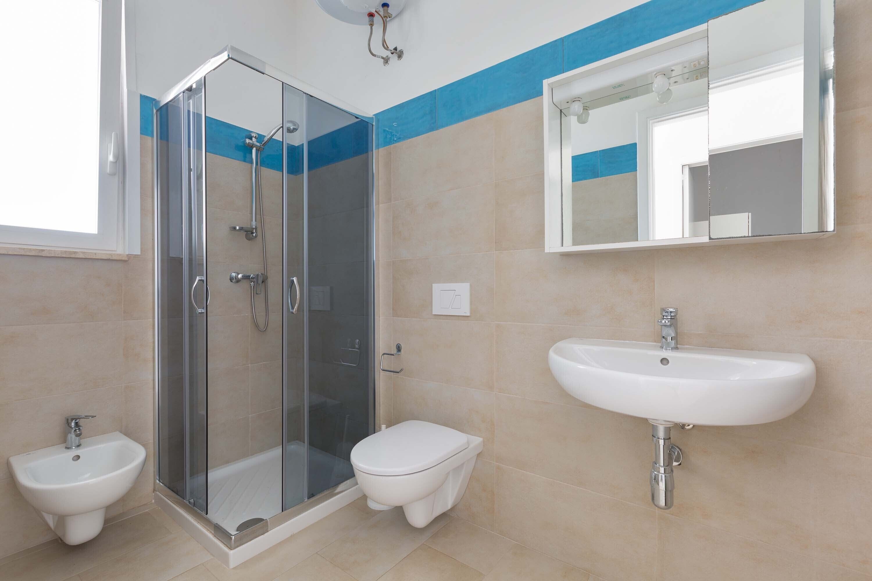 Een badkamer met een douchecabine van glas, een toilet en een wastafel.