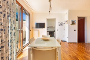 A modern kitchen with a flat-screen TV, wooden cabinets, and a dining area with a glass table and chairs. - Le Dune Villas (Porto Cesareo)