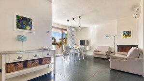 Ein modernes Wohnzimmer mit einer Couch, einem Essbereich mit Tisch und Stühlen sowie einer Küchenzeile mit Arbeitsplatte und Körben.
