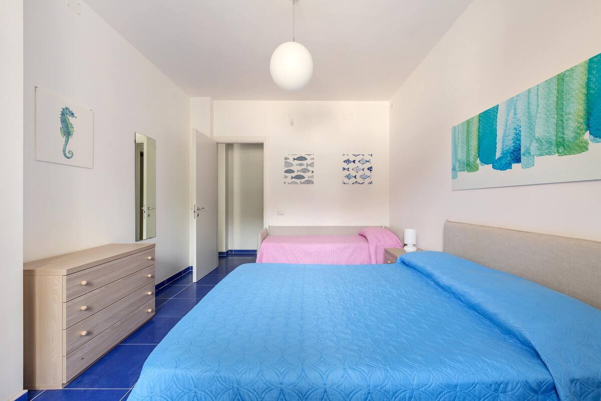 A bedroom with a large bed, a dresser, and artwork on the walls.