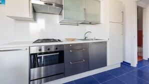A modern kitchen with stainless steel appliances, a white countertop, and a blue-tiled floor. - Residence Spiaggia d'Oro (Porto Cesareo)