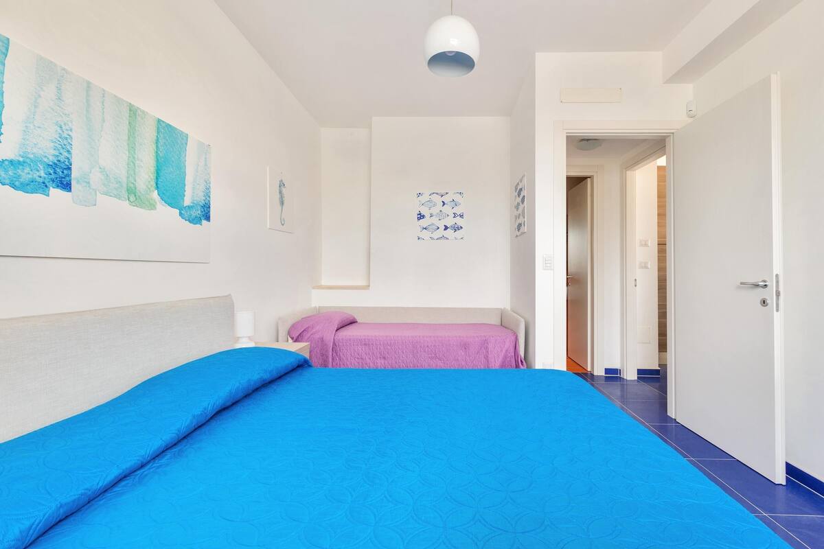 A bedroom with a large bed, a smaller bed, and a door leading to another room.