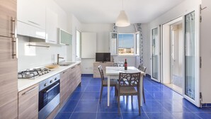 A modern kitchen with a dining area, a TV, and a large window. - Residence Spiaggia d'Oro (Porto Cesareo)