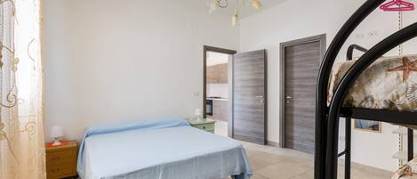 A bedroom with a bed, a nightstand, a dresser, a wardrobe, and a bunk bed.