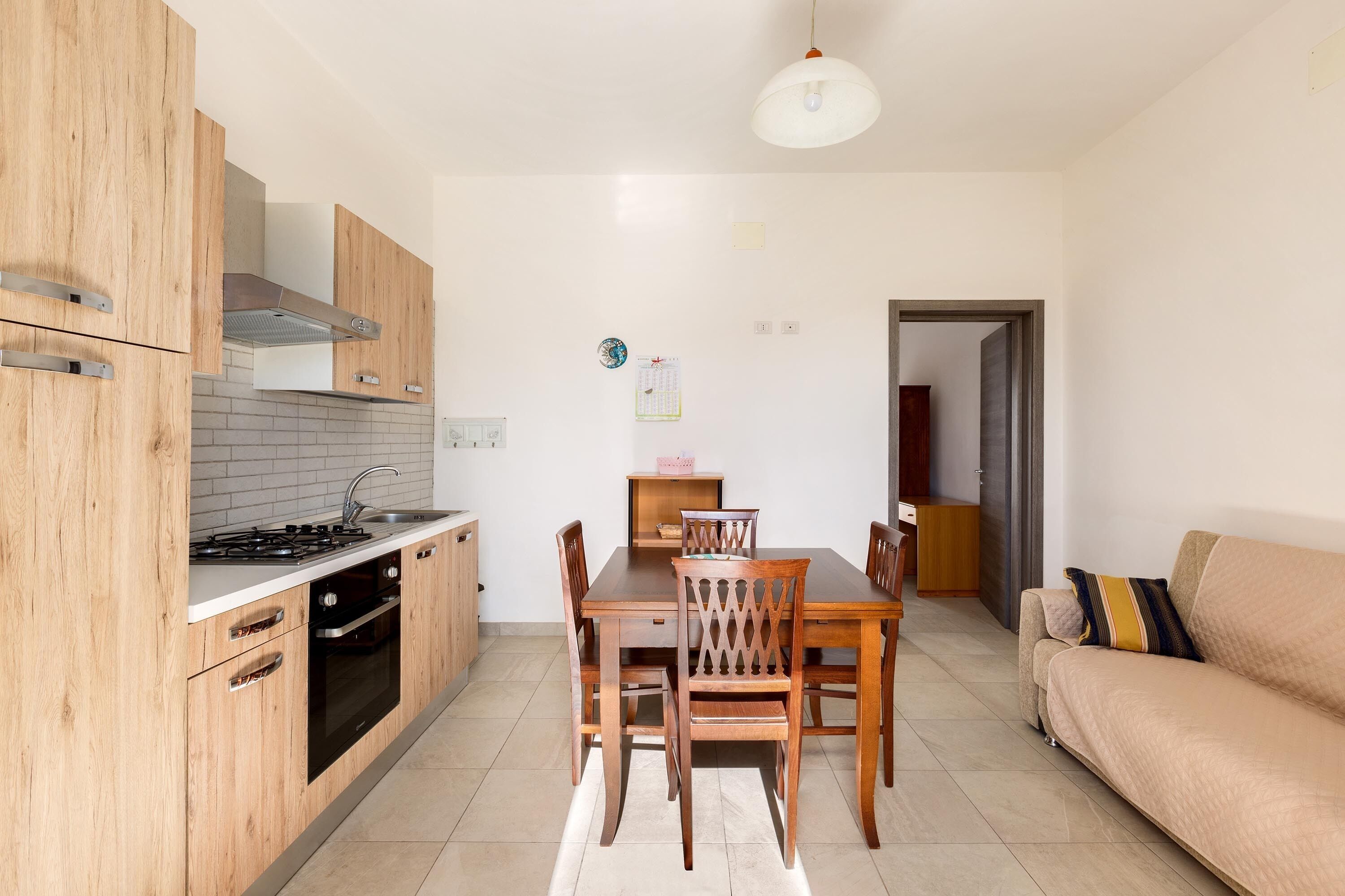 A modern kitchen with wooden cabinets, a gas stove, and a dining area with a table and chairs.
