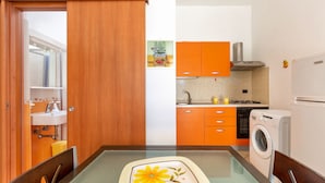 A modern kitchen with orange cabinets, a built-in oven, and a washing machine. - Villa Tulipano (Nardò)