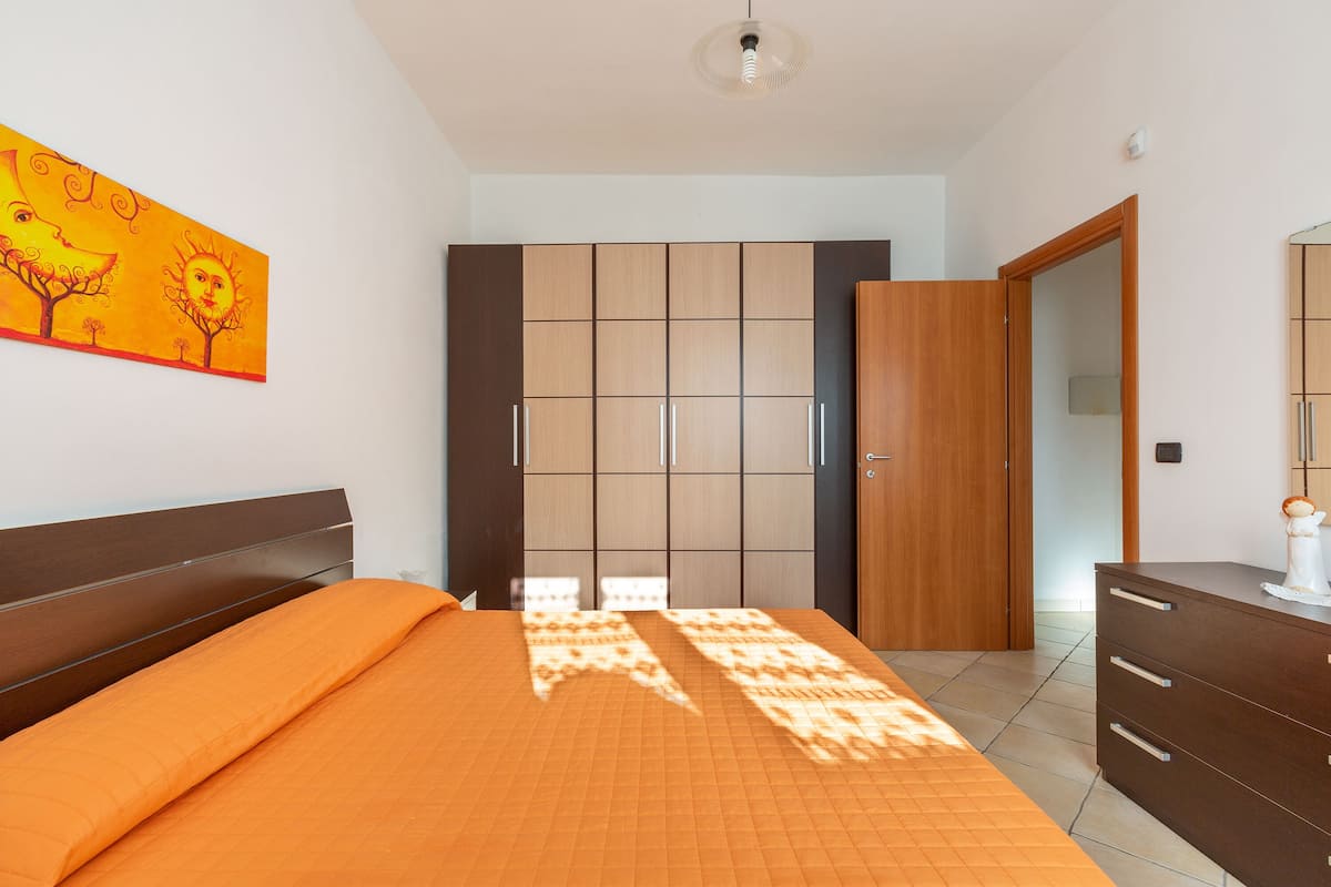 A bedroom with a bed, wardrobe, and dresser.