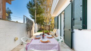 An outdoor patio with a table set for dining, a bottle of wine, and a chair. - Villa Tulipano (Nardò)