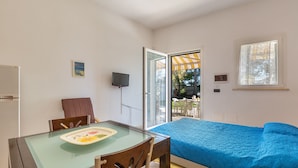 A bedroom with a bed, a glass-top dining table, a chair, a TV, and a window. - Villa Tulipano (Nardò)