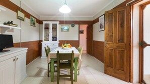 A dining area with a table set for two, a wooden door, and a white cabinet. - Villetta Spiaggia Bella (Lecce)