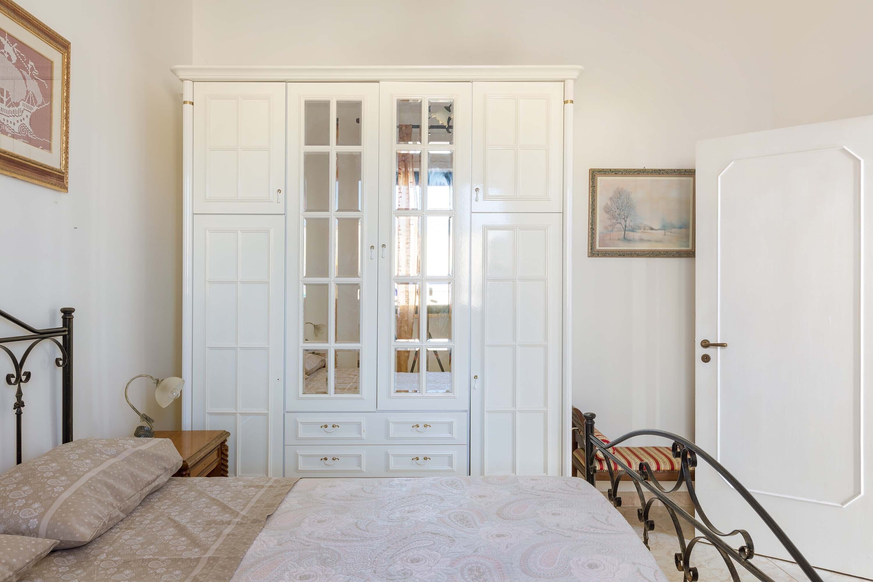 Een slaapkamer met een bed, een kledingkast, een nachtkastje en een bedtafel.