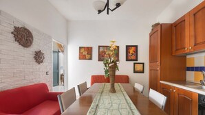 A dining area with a long table, red sofa, and wooden cabinets. - Villetta Albachiara (Porto Cesareo)