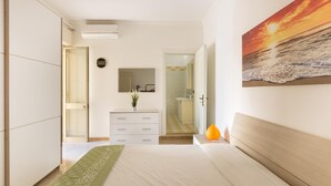 A bedroom with a bed, a dresser, a mirror, and a painting of a sunset over the ocean. - Villa Alessandra (Porto Cesareo)
