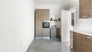 A modern kitchen with wooden cabinets, a built-in oven, and a microwave. - Appartamento Giada (Porto Cesareo)