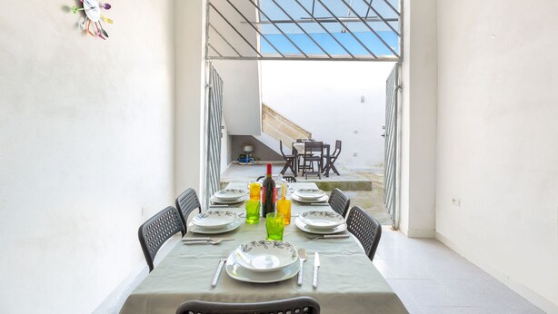 A dining area with a table set for six, chairs, a window, and a view of the outside. - Appartamento Giada (Porto Cesareo)