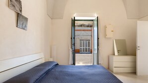 A bedroom with a bed, a dresser, a mirror, and a door leading to an outdoor area. - Appartamento Giada (Porto Cesareo)