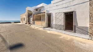 A row of modern buildings with balconies, a paved street, and a clear view of the sea. - Appartamento Giada (Porto Cesareo)