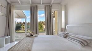 A bedroom with a large bed, a bedside table, and a view of the outdoors. - 1738 Tenuta degli Ulivi by Perle di Puglia (Melendugno)