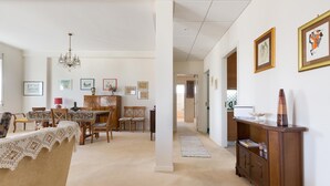 Een ruime woonkamer met een eethoek, een kroonluchter en een houten kast met kunstwerken.