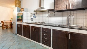 Una cocina con armarios de madera oscura, una campana extractora de acero inoxidable, un horno empotrado y un lavamanos.
