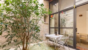 A patio area with a table and chairs, a potted plant, and a sliding glass door leading to an interior space. - Appartamenti Ai Fiorentini (Lecce)
