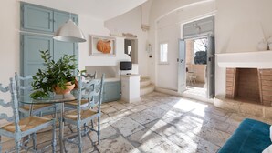 A spacious kitchen with a dining area, featuring a glass table, blue chairs, and a potted plant. - Villa Thea Charming House (Carovigno)