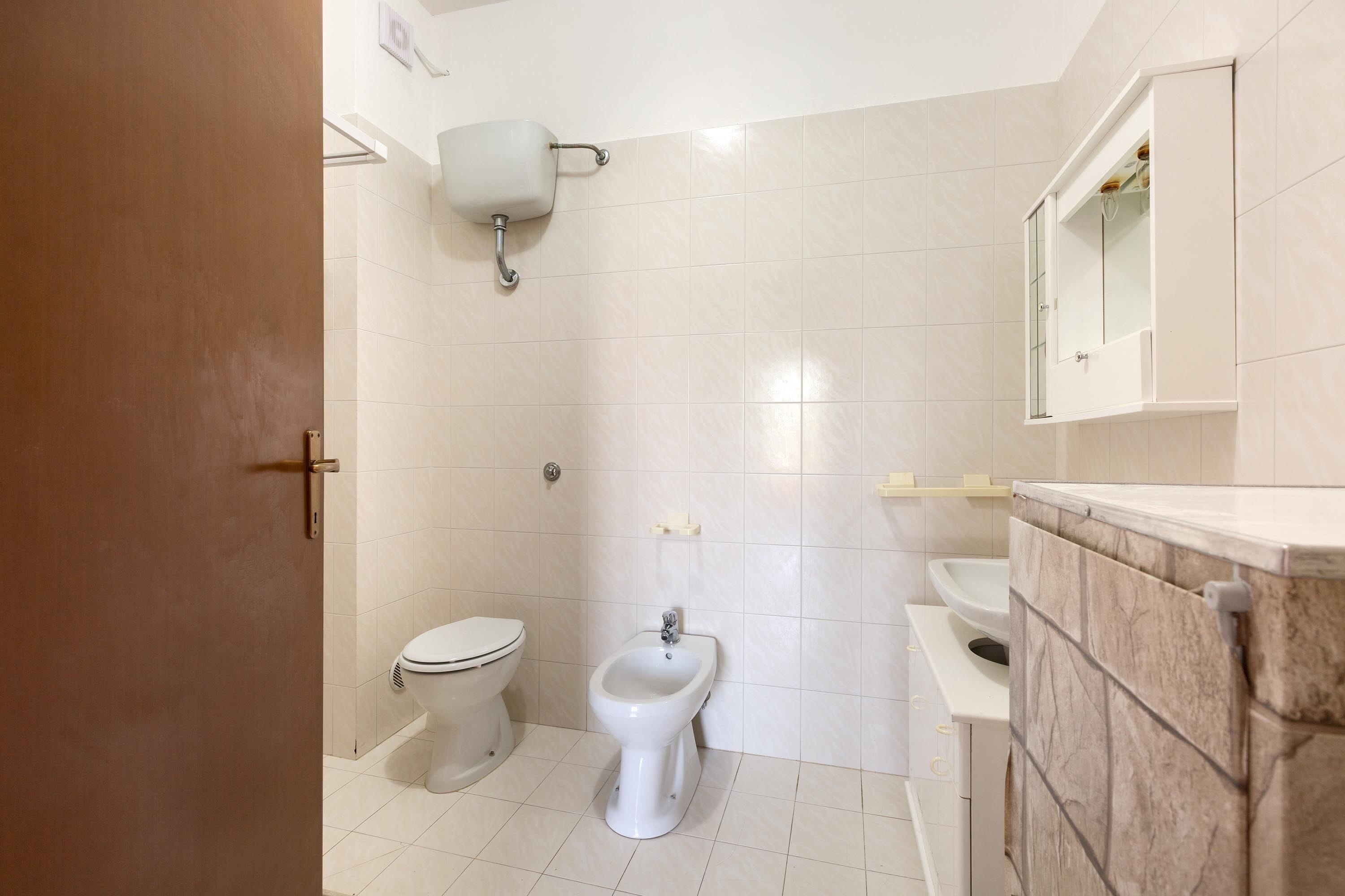 A bathroom with a toilet, bidet, and a mirror cabinet.