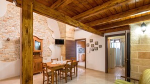 A dining area with a wooden table and chairs, a brick wall, and a stone fireplace. - La Nicchia di Luana (Copertino)