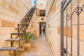 A narrow stone corridor with a metal staircase leading to an upper level.