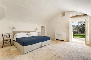 A bedroom with a bed, a chair, a lamp, and a radiator.