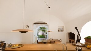 Een moderne keuken met een houten aanrecht, een roestvrijstalen spoelbak en hanglampen. Door een boog is een eethoek zichtbaar.