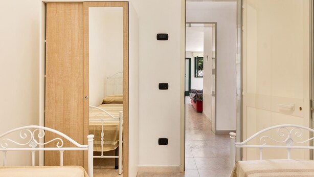 A bedroom with a bed, a wooden door, and a white wall.