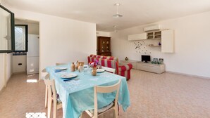 A dining area with a table set for four, a sofa, and a TV on a stand.