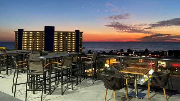 A rooftop bar with outdoor seating, overlooking a sunset over the ocean. - Cambria Hotel St Petersburg-Madeira Beach Marina (Madeira Beach)