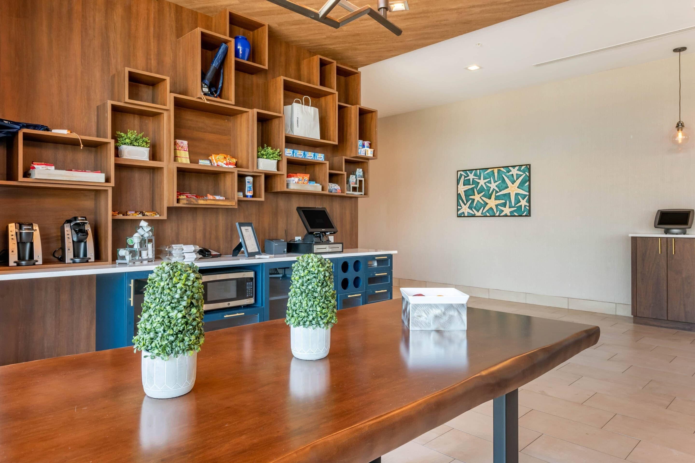 A modern kitchen with wooden shelving, a wooden dining table, and two potted plants.