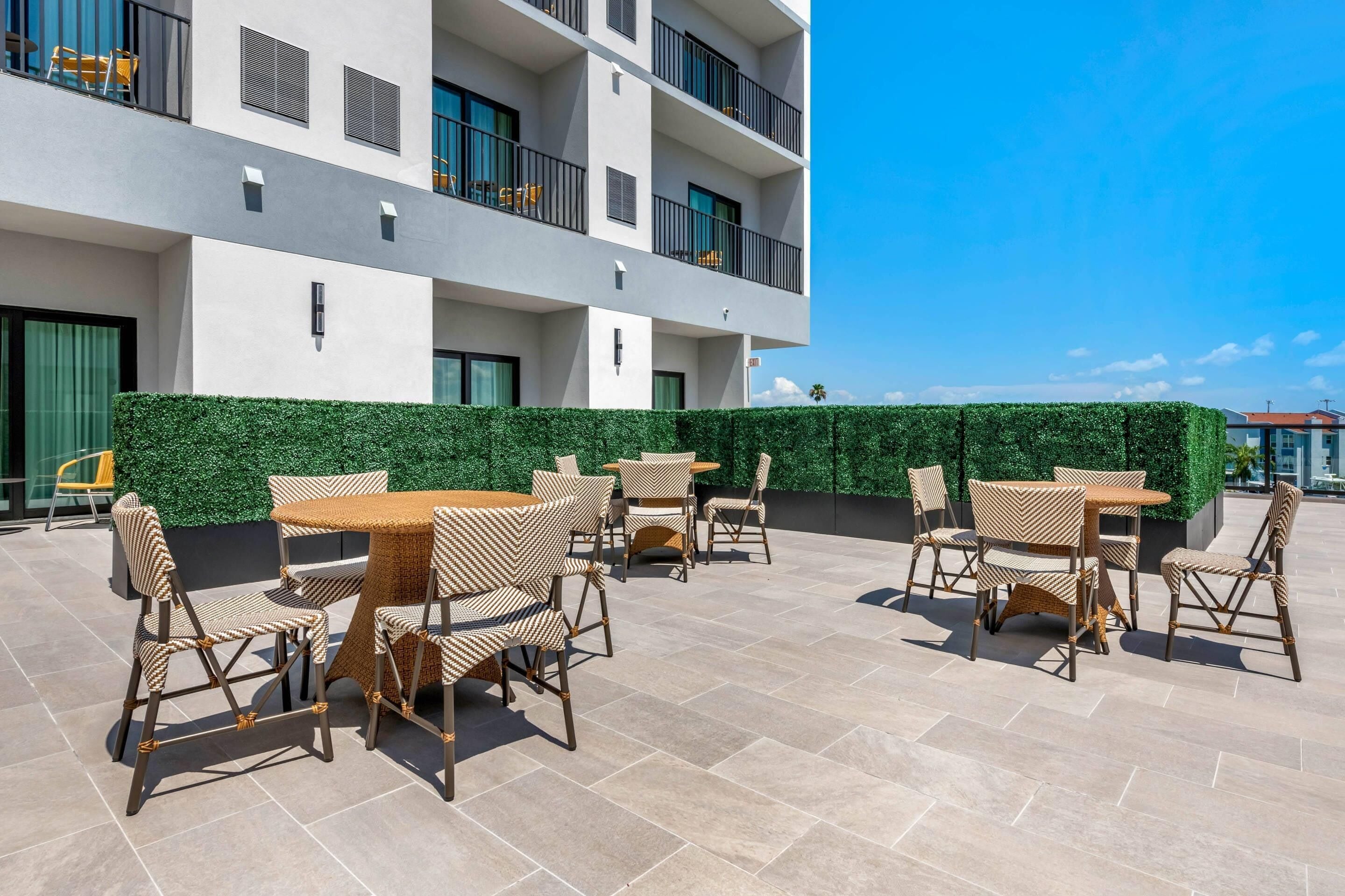 Eine Terrasse im Freien mit Korbmöbeln und einer grünen Hecke.