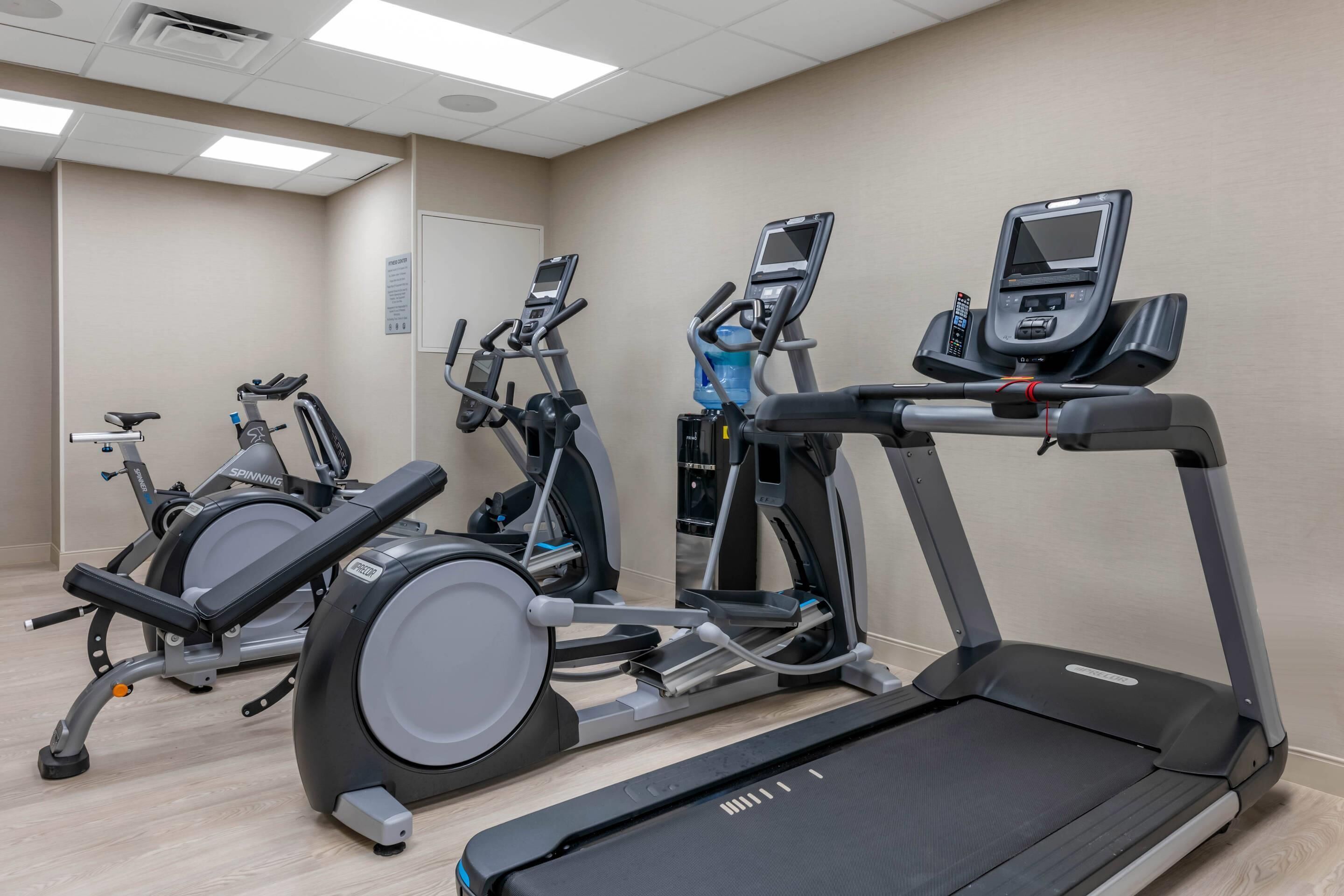 A gym with multiple exercise machines including treadmills and stationary bikes.