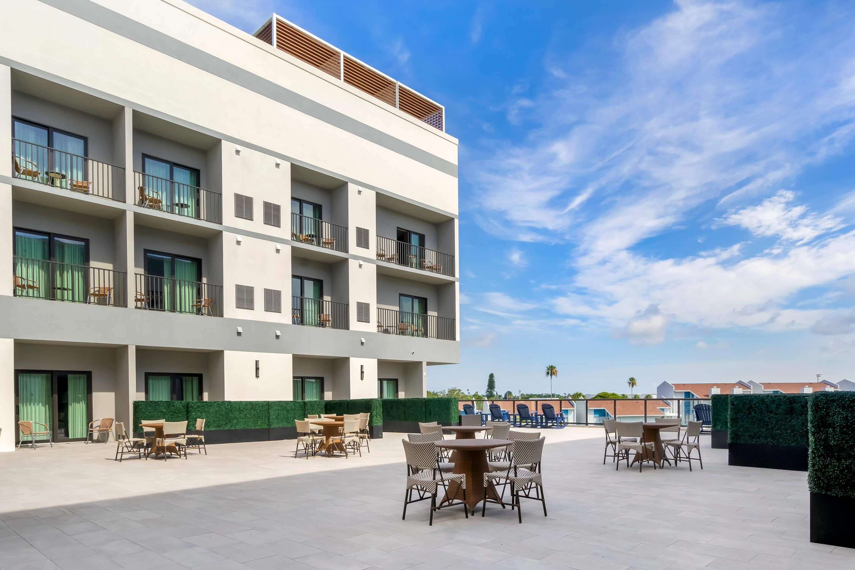 Un hotel moderno con varios balcones, zonas de estar al aire libre y una vista despejada del cielo.