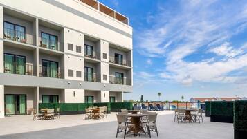 Un hotel moderno con varios balcones, zonas de estar al aire libre y una vista despejada del cielo.