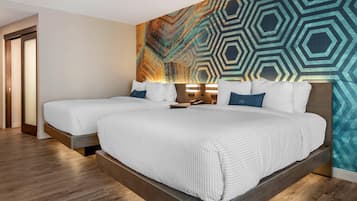 A hotel room with two beds, a large geometric patterned wall, and a wooden floor.