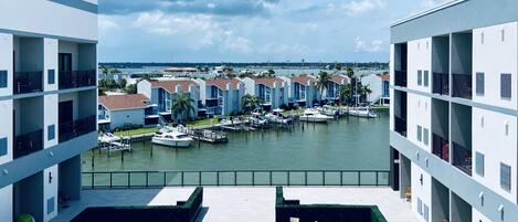 Un puerto deportivo con barcos amarrados, vista al agua y un edificio con varios balcones y mesas al aire libre.