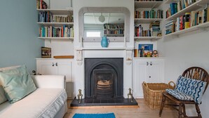 Un salon avec une cheminée, des étagères à livres, un canapé et un fauteuil.