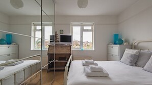 Une chambre à coucher avec un lit, un bureau, une chaise, une télévision et une fenêtre.