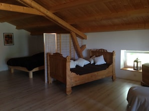 A wooden bed in a room with a sloped ceiling and a window.