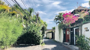 A narrow street lined with lush greenery and a building with a sign reading "Villa Retro". - VILLA RETRO 88 - Short Walk to Beach - Top Located (Seminyak)