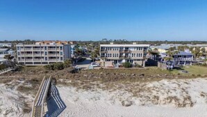 Um imóvel à beira-mar com edifícios de vários andares, uma praia de areia e uma passarela para pedestres.