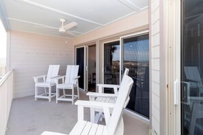 A covered outdoor area with white chairs and a ceiling fan.