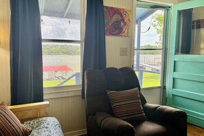 Une pièce avec vue sur un quai, une chaise avec un coussin à rayures et un tableau accroché au mur.